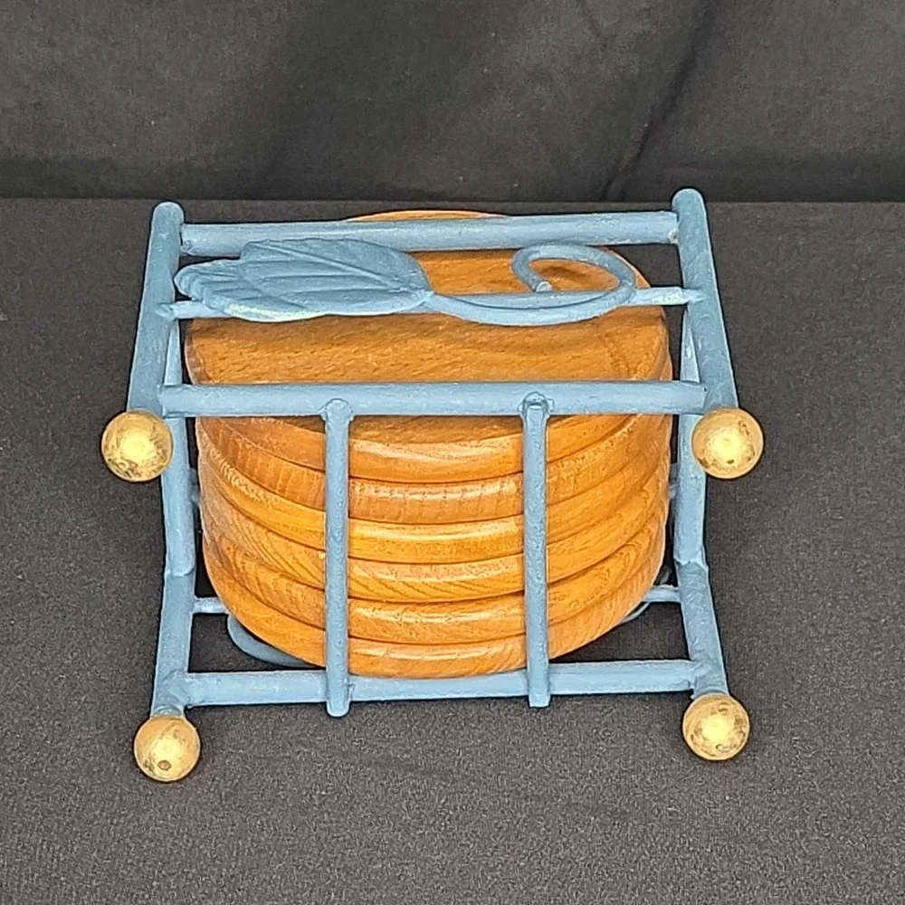 a vintage wooden drink coasters in a blue metal  holder with leaf-shaped accents